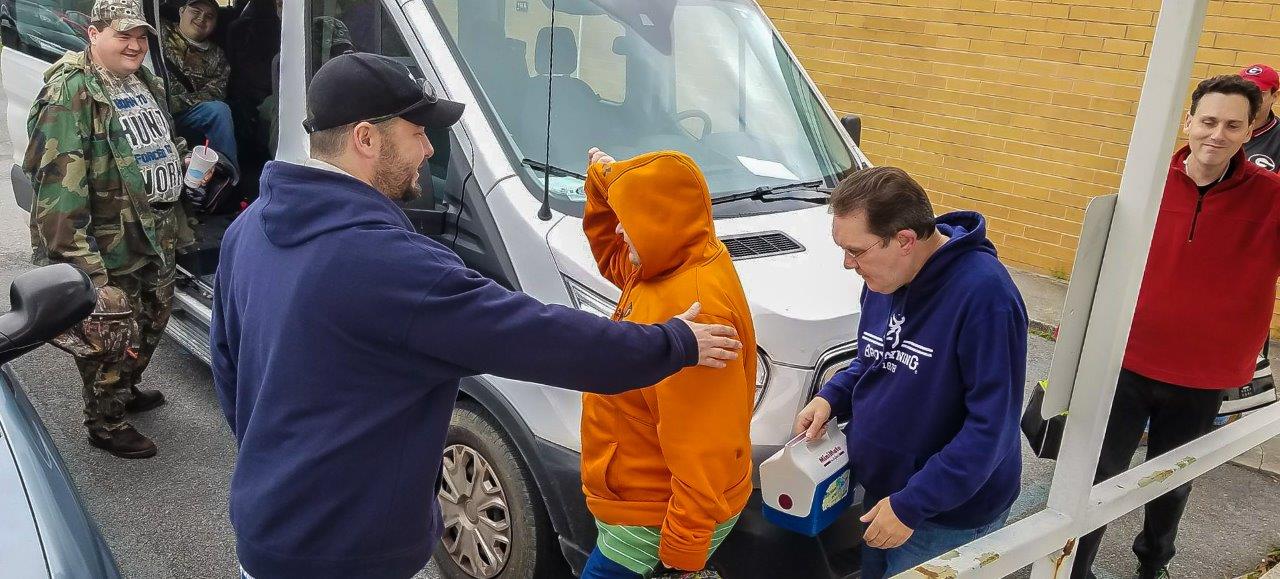 Orange Grove Center’s Lead Direct Support Professional Blake Clark (helping people around the front of the shuttle bus) is one of several who assists these adults at the Georgia Northwestern Technical College location in Walker County, Georgia. This is a scene at the end of the day as Orange Grove Center clients climb on board a van that provides transportation to and from the new facility.