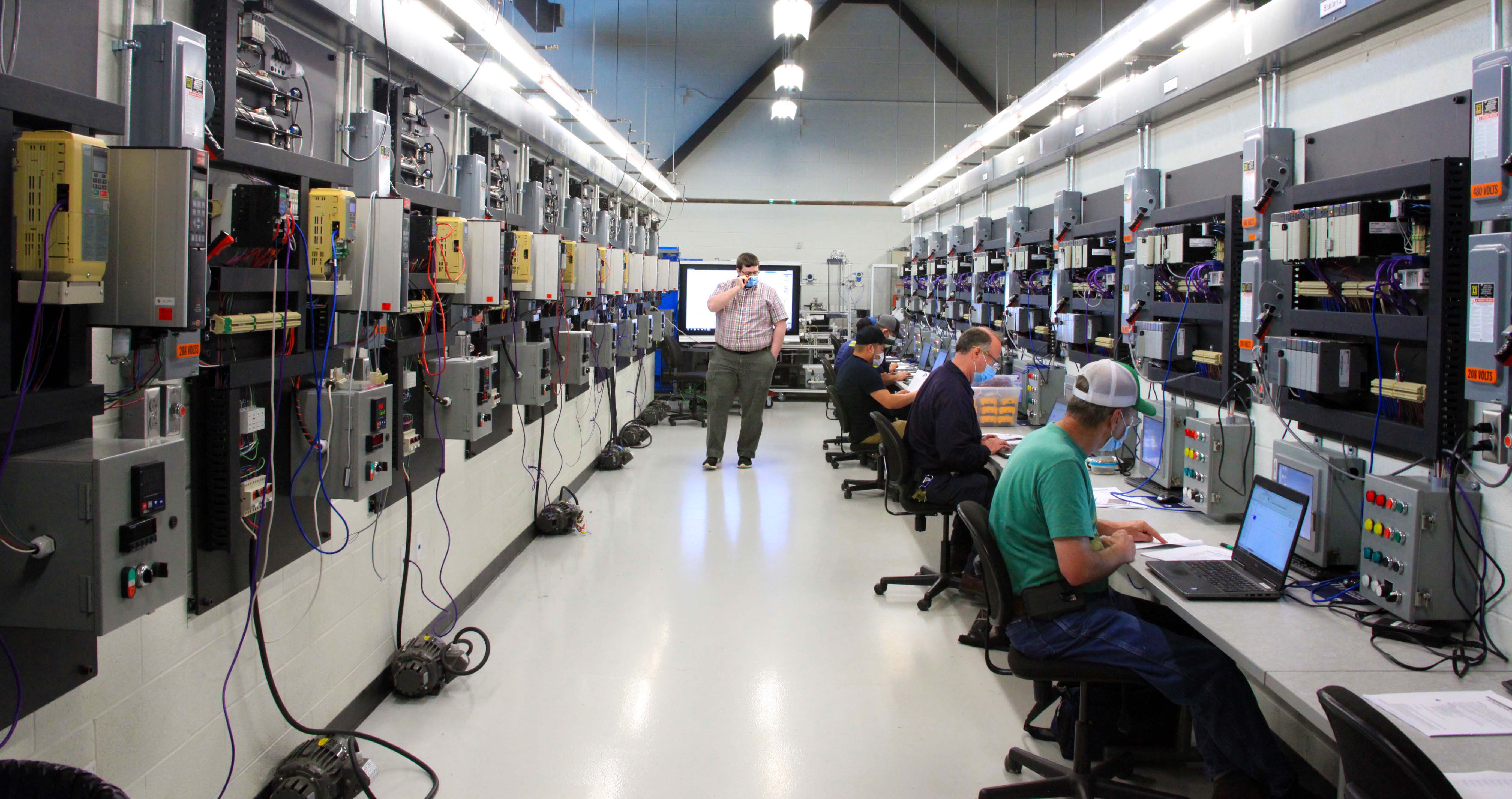 Cody Brewer (center), GNTC’s Instrumentation and Controls instructor, watches over the PLC trainees during an evening continuing education session.