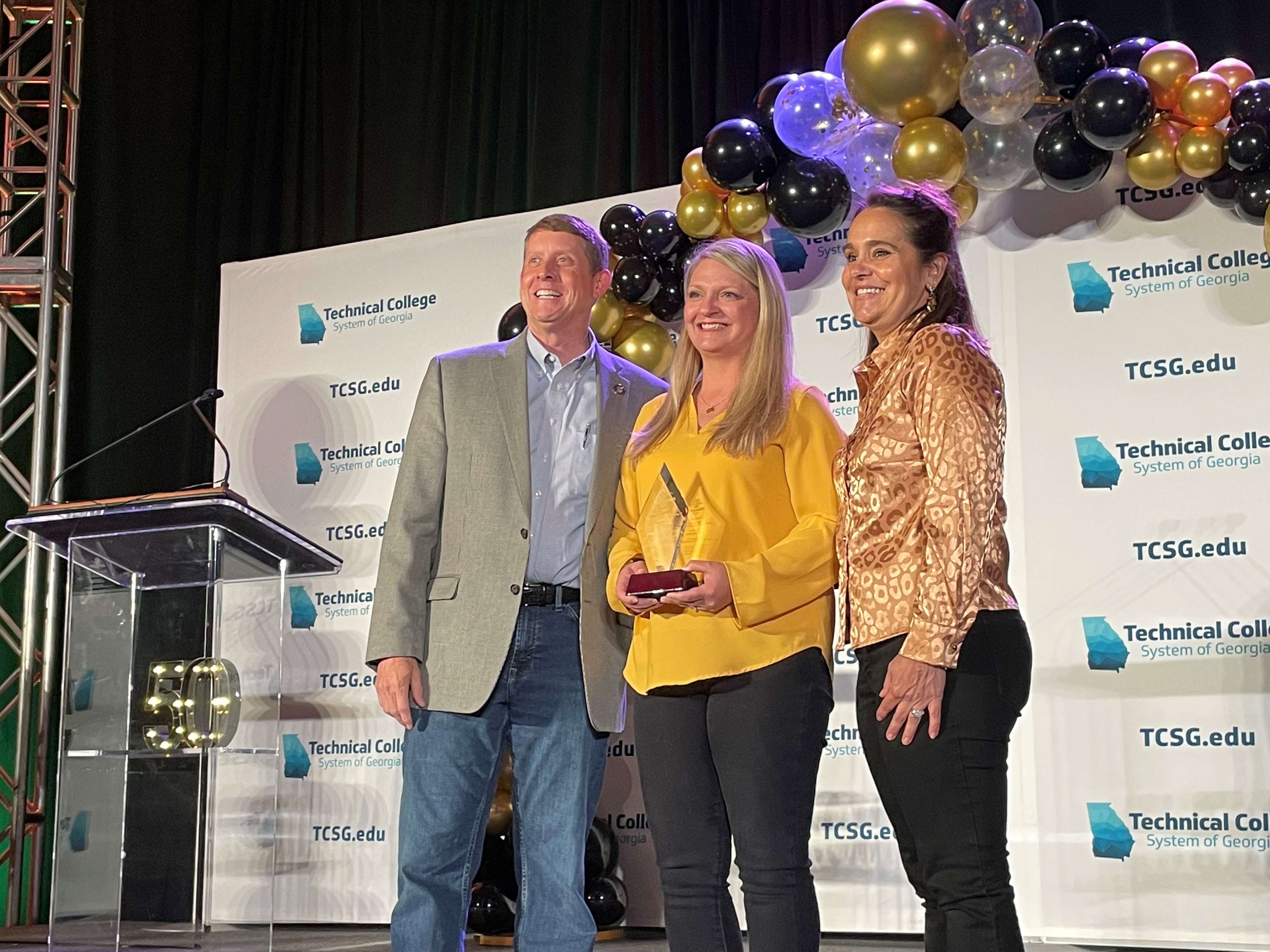 TCSG Commissioner Greg Dozier (left) and 2021 Rick Perkins Award recipient Casey Corbett (right) pose with Crista Resch, GNTC instructor and director of Ultrasound programs, who was selected as one of nine regional finalists for Rick Perkins Instructor of the Year. The winner of the state award will be announced on Wednesday, April 27.