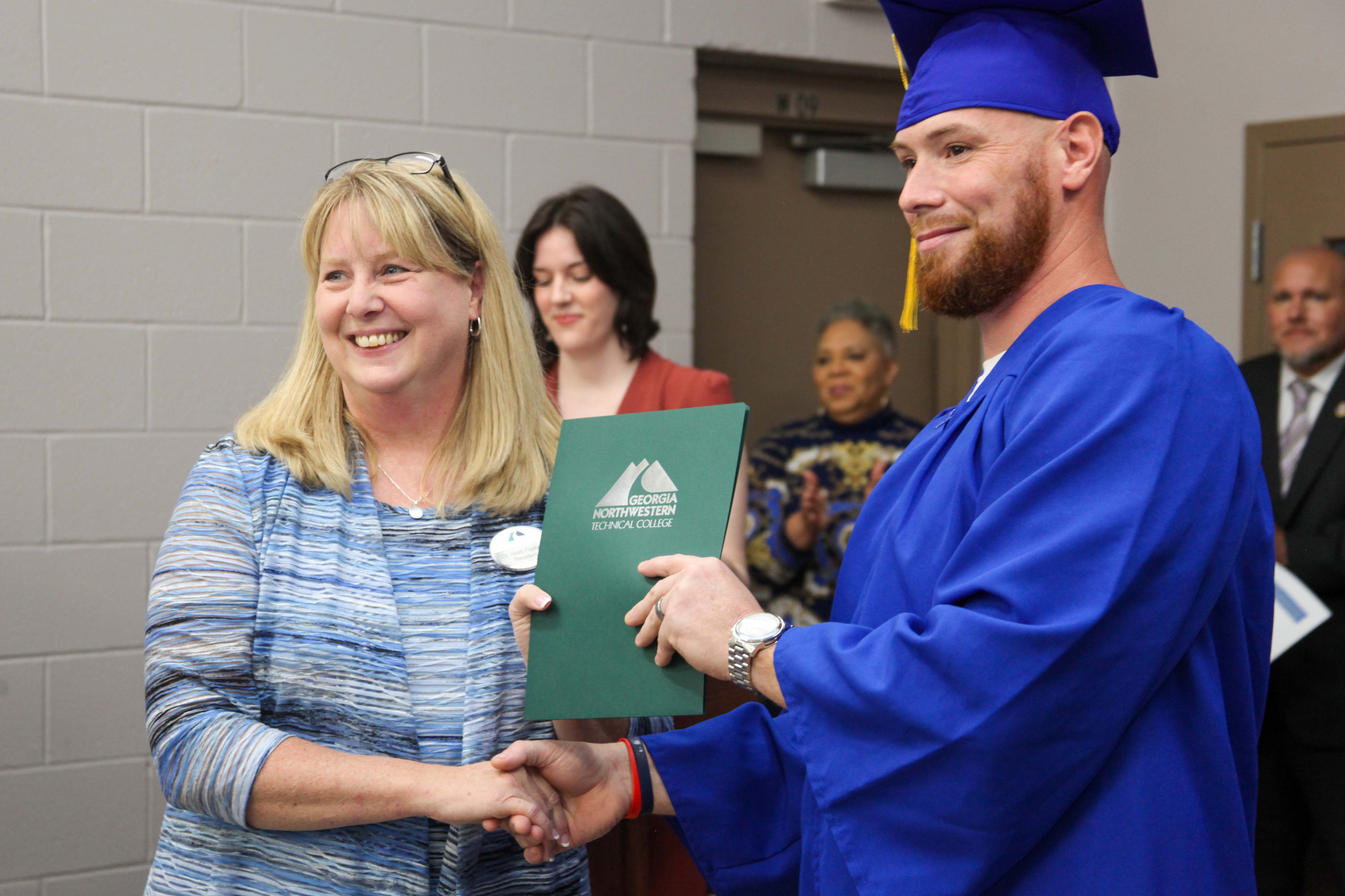 GNTC President Dr. Heidi Popham (left) hands Kyle Edmunds a Certificate of Completion from GNTC for completing the 135-hour welding training program at the Floyd County Prison.