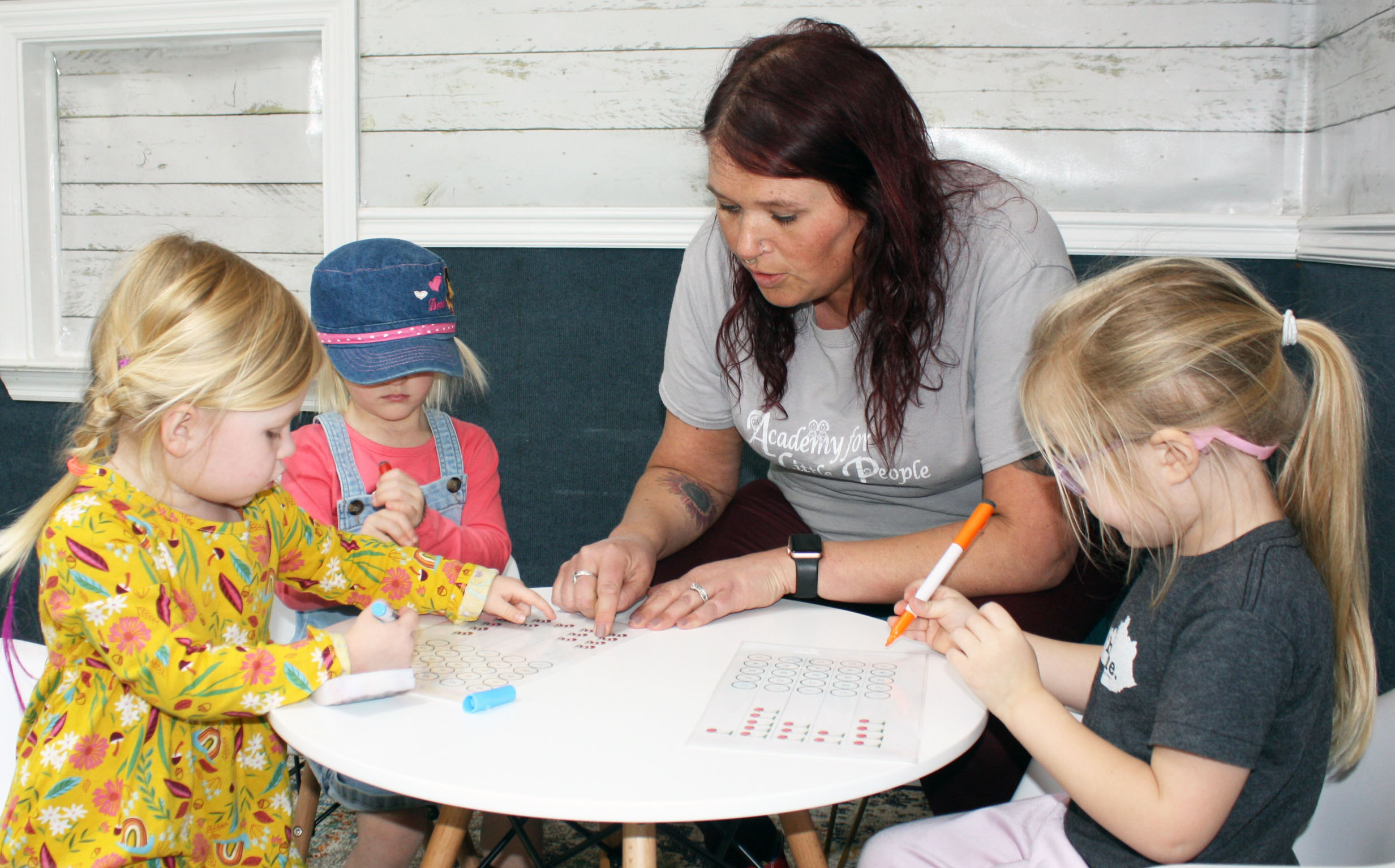 Hannah Beth Reeves assists Academy for Little People students (from left) Reese Robertson, Monroe Griffin and Parker Baugh with a counting exercise.