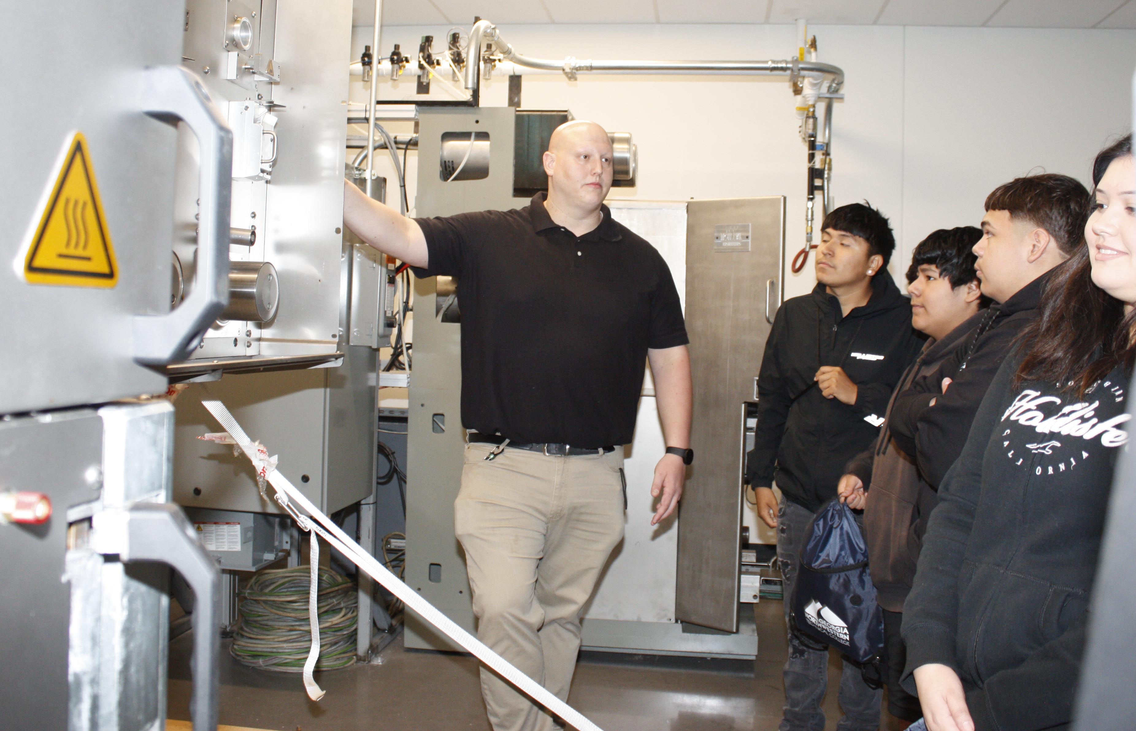 Dustin Tate, Carpet Training and Floor Production instructor and program director at GNTC (left), explains the carpet production process to students.