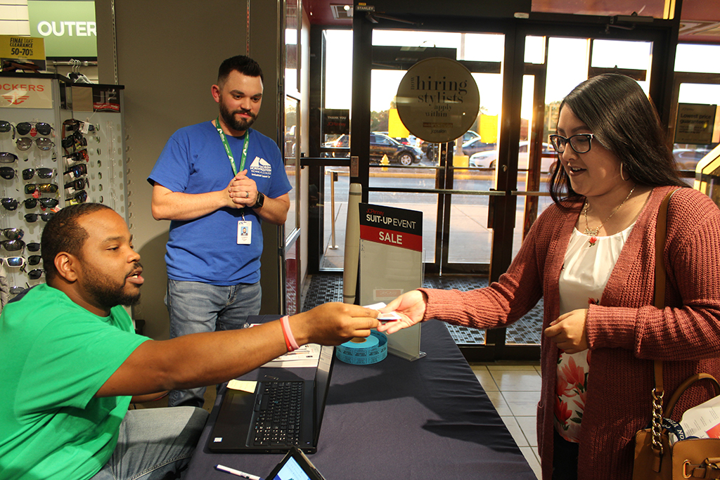 Larry Blanchard (left), strengthening institutions program coordinator, hands Daisy Reyes (right), a GNTC student working on an associate degree in Medical Assisting, a J.C. Penny gift card during the college’s Suit-Up event Saturday evening. Legare Price, director, enrollment services, watches after making the announcement Reyes had won a prize.