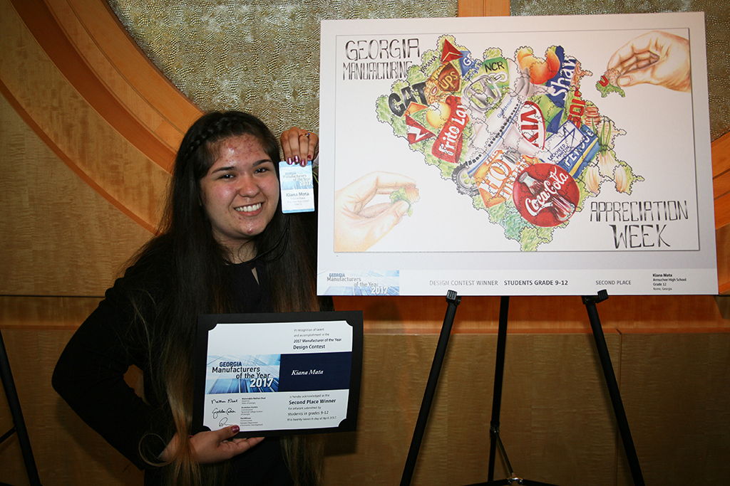 Kiana Mata stands beside her artwork that won second place in the 2017 Manufacturing Appreciation Week (MAW) statewide student design contest in the ninth through twelfth grade category.