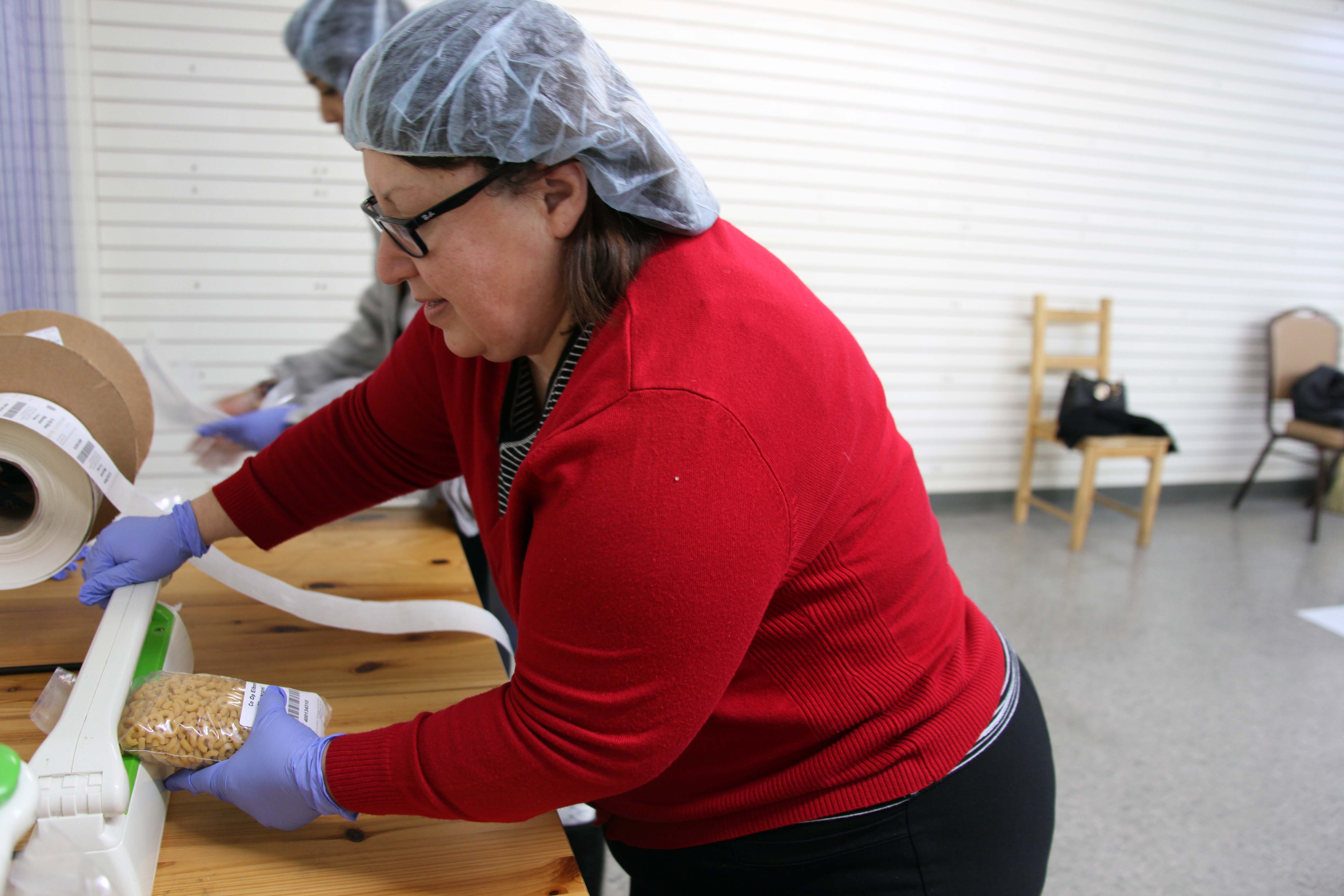 Georgina Valderrama, Phi Beta Lambda coordinator, uses a heat sealer to secure a 12-ounce bag of macaroni noodles at the Northwest Georgia Branch of the Chattanooga Area Food Bank on Wednesday, Dec. 11. 