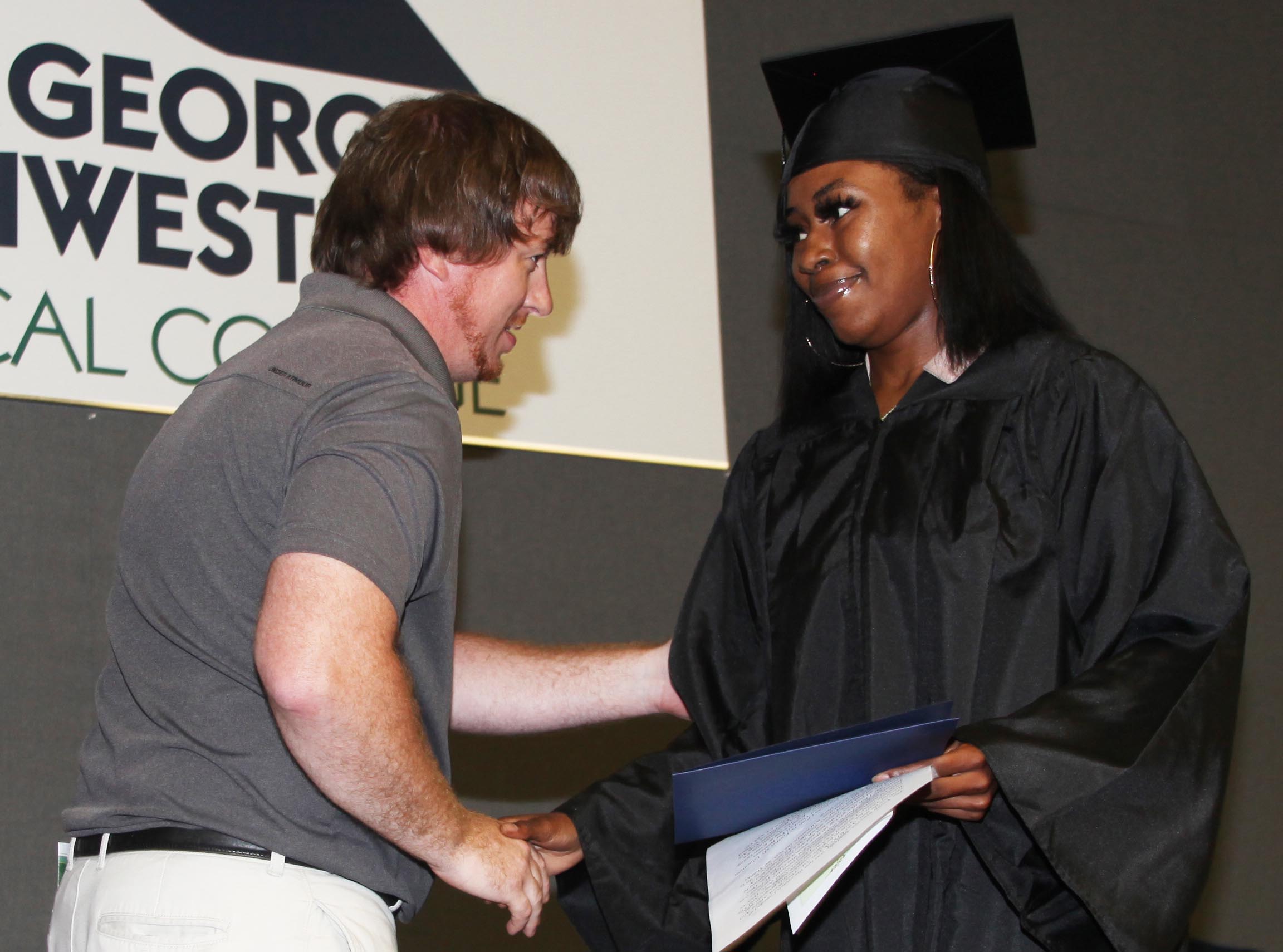 GNTC Youth Services instructor Erick Hopper (left) congratulates Destany Monroe, who was student speaker at the Youth Success Academy graduation at GNTC’s Floyd County Campus. 