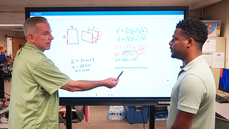 (From left) Marty Moorehead, and Marco Issonne use the touch display whiteboard, which was donated by Newline Interactive Inc.